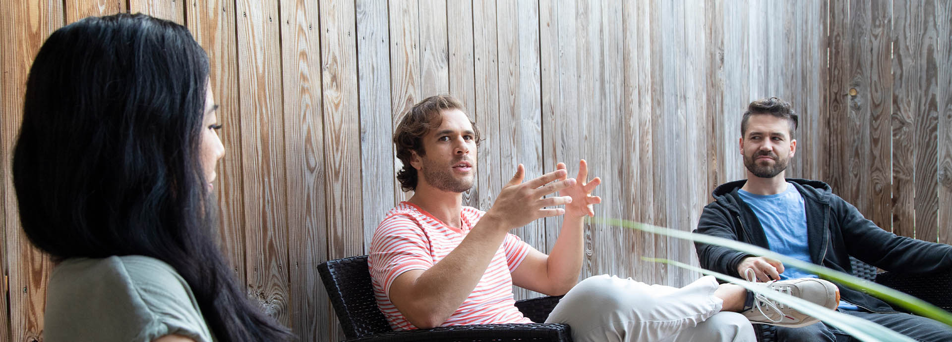 group of young adults chatting outside sitting in chairs on a patio